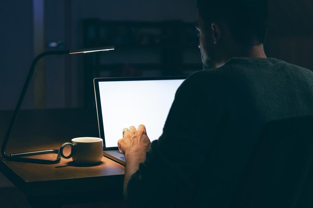 man-sits-dark-room-front-blank-laptop-screen_169016-48879